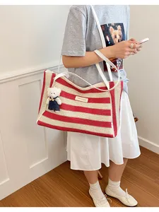 Détail du sac cabas en paille rayé rouge et blanc avec grande capacité et joli pendentif d'ours.