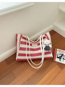 Vue détaillée d'un sac cabas rayé rouge et blanc avec des bretelles blanches et un pendentif.