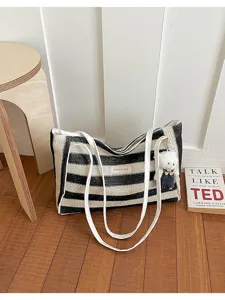 Détail du sac cabas en paille rayé noir et blanc, avec lanières blanches et joli pendentif.