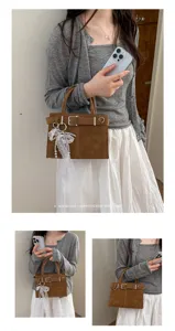 Detailaufnahme der retro braunen Handtasche mit edlem Perlenanhänger und Riemendesign.