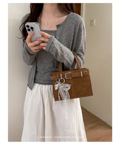 Retrospektive braune Umhängetasche für Damen, stilvolle Tasche mit Schnalle und Spitzenanhänger.