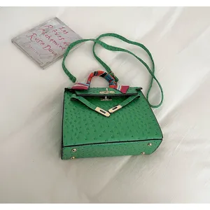 Green ostrich pattern Kelly bag detail, elegant top handle handbag with chic scarf accent.