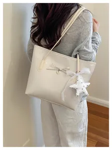 Detail shot of a chic beige PU leather tote bag with bow and star pendant for women.
