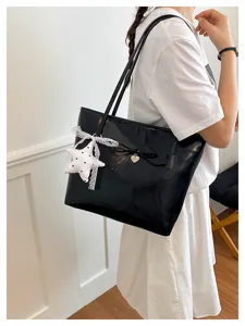 Detail view of a black oil leather shoulder bag featuring a cute bow and lace star pendant.