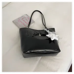 Close-up of black PU leather tote bag with elegant bow knot and star pendant accessory.