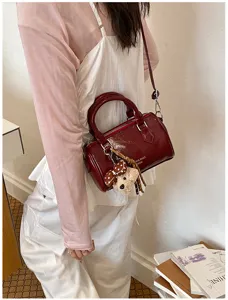 Dark red patent leather Boston shoulder bag with cute bear charm detail for daily commuting.