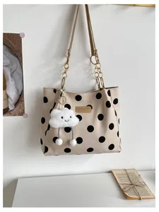 Close-up detail of beige polka dot tote bag with cute cloud keychain and chic chain strap.