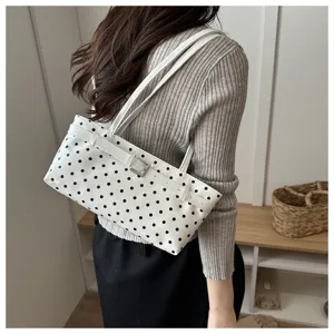 Detailed view of a stylish white polka dot patent leather shoulder bag with a sleek buckle.