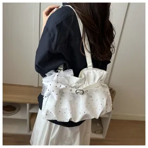 White pleated shoulder bag with silver star print, buckle strap and lace star charm detail.