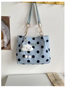 Close-up detail of stylish blue polka dot shoulder tote bag with cute cloud pendant.