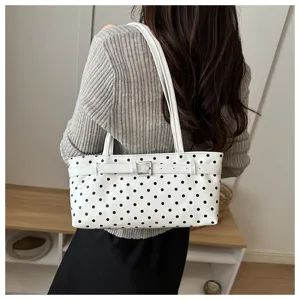 Chic white polka dot patent leather shoulder bag with a decorative buckle strap detail.