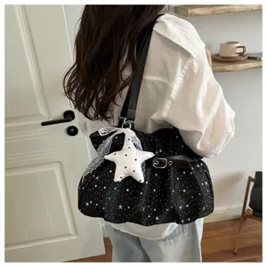 Close-up detail of the black star print shoulder bag with lace trim and star pendant.