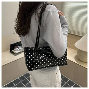 Detail view of the stylish black patent leather polka dot shoulder bag with buckle strap.