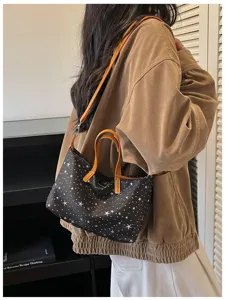 Detailansicht einer modischen Sternenprint Canvas Schultertasche mit braunen Griffen.
