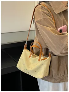 Detailansicht einer modischen gelben Umhängetasche mit Sternen und braunen Henkeln.