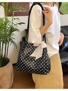 Vista detallada del bolso de hombro con lunares negros, bolso elegante y práctico.