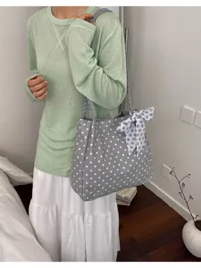 Detalle de bolso tote de lunares grises, con asas trenzadas y pañuelo floral decorativo.