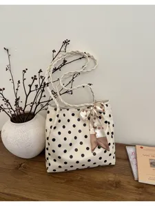 Vista detallada del elegante bolso tote de lunares con asa trenzada chic y cinta decorativa.