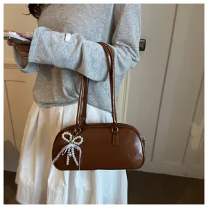 Primer plano detallado de bolso de hombro vintage de cuero encerado marrón con elegante colgante de lazo.