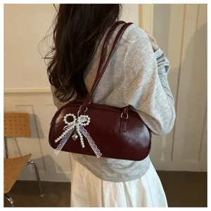 Vista detallada del bolso de charol burdeos retro con elegante colgante de lazo de perlas y encaje.