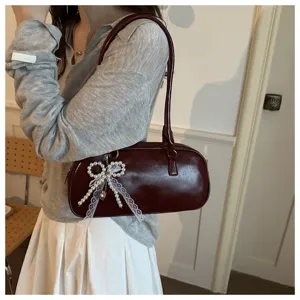 Vista detallada del bolso baguette de hombro de charol retro para mujer con lazo de perlas.