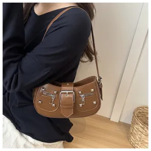 Dettaglio borsa a spalla in pelle PU marrone con borchie metalliche, tasche con zip e fibbia.