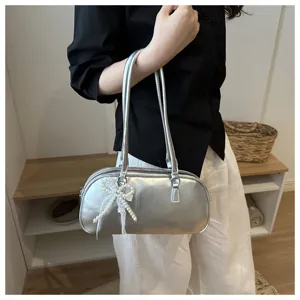 Bolso de hombro baguette de cuero encerado plateado con lazo de perlas vista detallada.