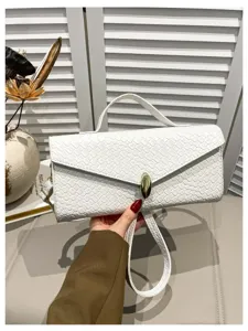 Detailaufnahme der eleganten weißen Handtasche mit Flechtmuster, goldenem Schloss und Griff.