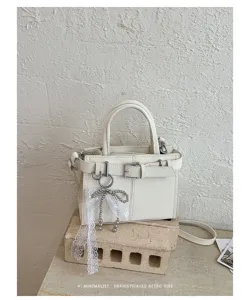 Detailaufnahme einer minimalistischen weißen Damentasche mit feinem Gürtel und Schleife.