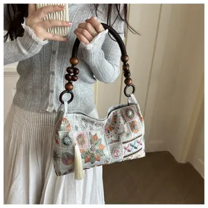 Detailansicht der eleganten bestickten Achseltasche mit Perlenhandgriff und Quastenanhänger.