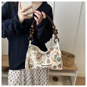 Schicke bestickte Canvas-Umhängetasche mit Perlenhenkel und boho floralen Mustern.