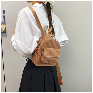 Detail view of the brown plaid mini backpack, featuring a front pocket and soft straps.