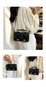 Closeup details of the black polka dot shoulder bag with gold metal twist lock hardware.