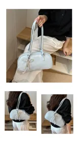 Detalle de bolso bajo brazo Boston de charol azul claro con colgante lazo de perlas.
