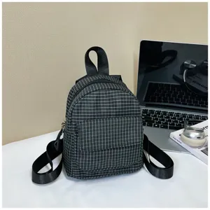 Detailed shot of a black and white grid mini backpack placed on a clean white desk with props.