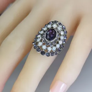 Close-up detail of statement cluster ring with purple center stone and opal rhinestones.
