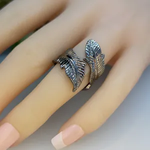 Close-up van de donkere metalen bladvormige open ring met gedetailleerde vintage textuur.
