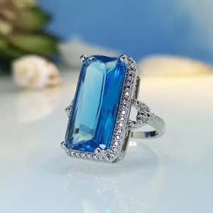 Exquisite emerald cut blue crystal ring detail shot, sparkling pavé zircon gemstone jewelry.