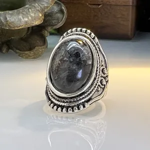 Vintage retro natural stone ring with intricate carved silver band and unique dark gemstone.