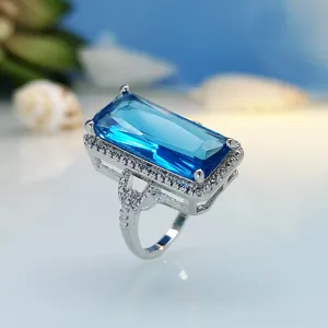 Detailed close-up view of a stunning rectangular light blue gemstone ring with sparkling pavé halo.