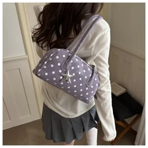 Detail shot of trendy purple polka dot bowling shoulder bag with cute star charm accessory.