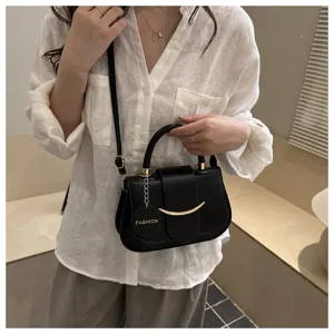 Detailopname van een zwarte stijlvolle crossbody tas met metalen handvat en gouden accent.