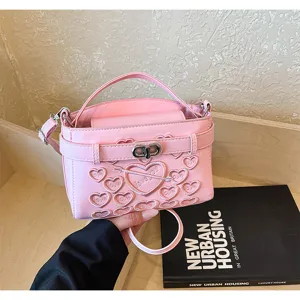 Detail view of the trendy pink embossed heart shoulder handbag with metal lock and handle.