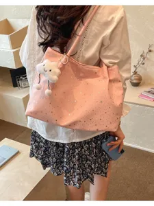 Detail shot of a cute pink star print tote bag with a soft cloud pendant charm, casual style.