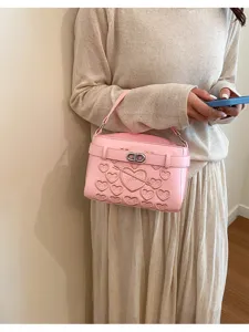Detailed shot of pink shoulder bag with heart embossing and metallic twist lock, chic fashion.