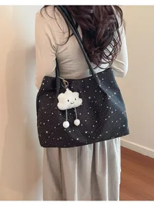 Detail view of black canvas tote bag with white star pattern and cute cloud plush keychain.