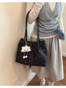 Detailed view of black star print canvas tote bag with cute white cloud plush pendant.