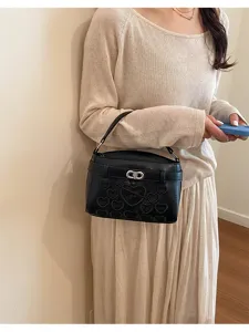 Black shoulder handbag with embossed heart pattern and metal twist lock for women daily use.
