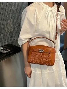 Detail view of brown shoulder bag with embossed hearts and love text, stylish accessory.
