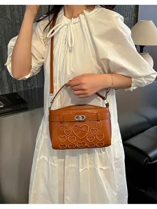 Detail view of stylish brown shoulder bag featuring embossed love heart patterns and metal lock.